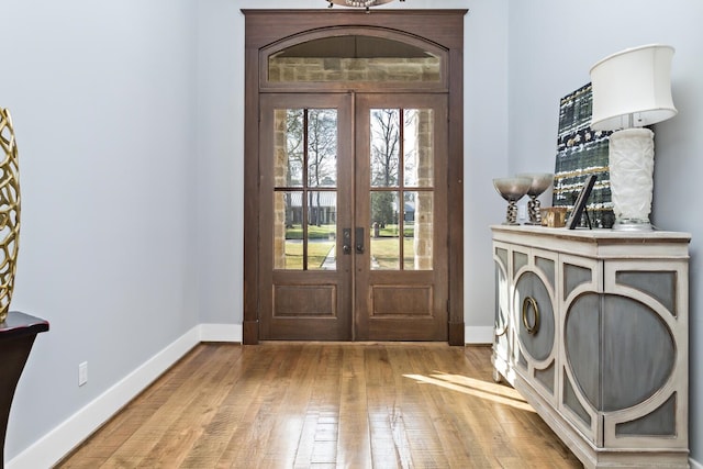 foyer featuring baseboards, hardwood / wood-style floors, and french doors