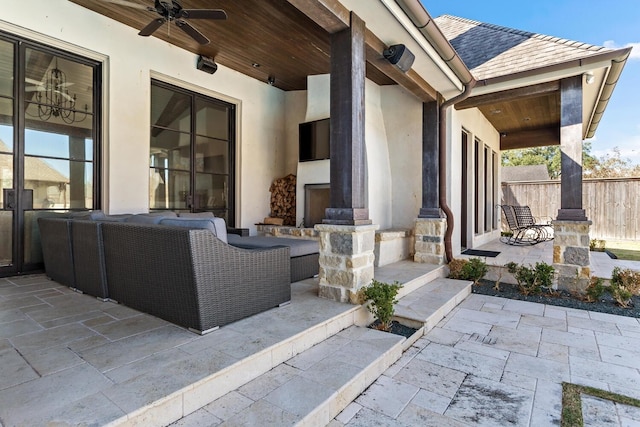 view of patio with ceiling fan, an outdoor living space with a fireplace, and fence