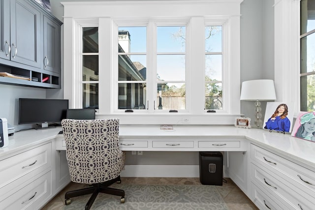 office with light tile patterned floors and built in study area