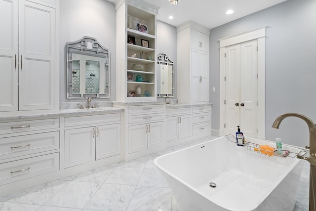 bathroom with a freestanding bath, double vanity, a sink, and marble finish floor