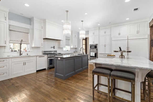 kitchen featuring dark wood finished floors, a center island with sink, visible vents, appliances with stainless steel finishes, and white cabinets