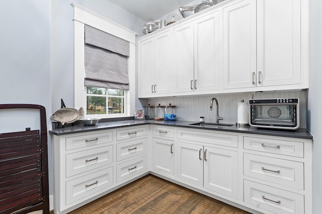 kitchen featuring dark countertops, a sink, and white cabinetry