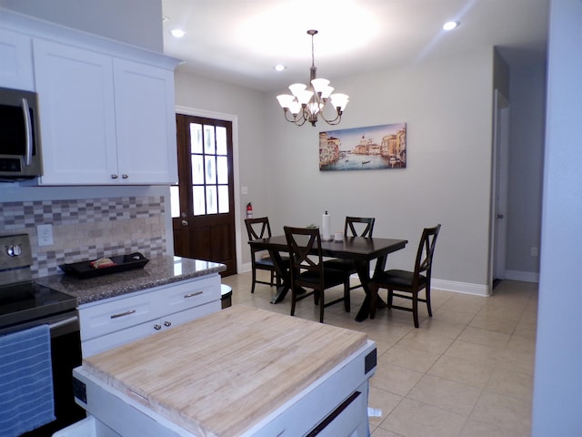 4261 Carlene Dr, Orangefield, TX 77630 - kitchen featuring appliances with stainless steel finishes, backsplash, a chandelier, light tile patterned floors, and white cabinetry