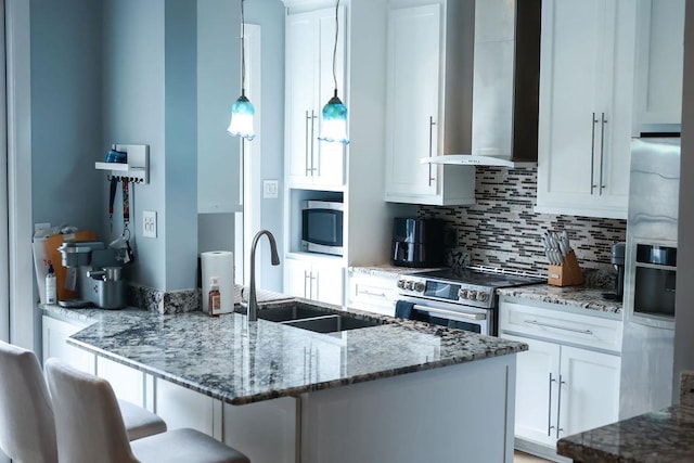 1620 Wellington Pl, Beaumont, TX 77706 - kitchen featuring appliances with stainless steel finishes, wall chimney range hood, decorative backsplash, white cabinets, and a kitchen bar