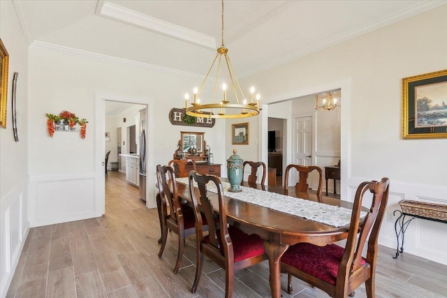 dining room with light wood-type flooring, a raised ceiling, ornamental molding, and an inviting chandelier