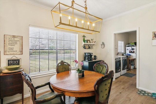 dining room with light wood-type flooring, a chandelier, washing machine and dryer, and ornamental molding