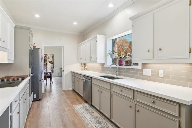 kitchen with crown molding, light hardwood / wood-style flooring, sink, white cabinetry, and stainless steel appliances