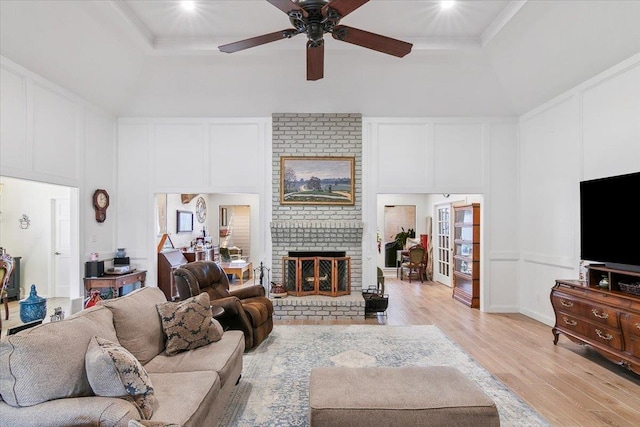 living room with a fireplace, crown molding, light wood-type flooring, and a raised ceiling