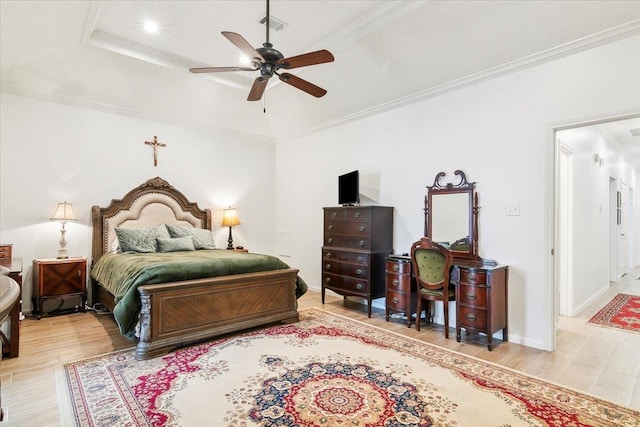 bedroom with crown molding, light hardwood / wood-style flooring, a tray ceiling, and ceiling fan