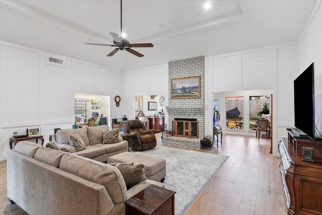 living room with a fireplace, light wood-type flooring, a tray ceiling, and ornamental molding