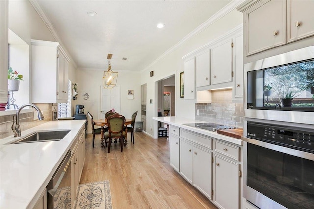 kitchen with sink, decorative light fixtures, white cabinetry, and stainless steel appliances