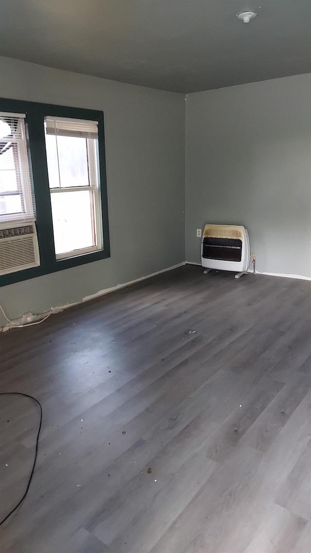 empty room with heating unit, cooling unit, and hardwood / wood-style flooring