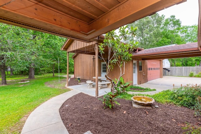view of patio / terrace with fence, an attached garage, and driveway