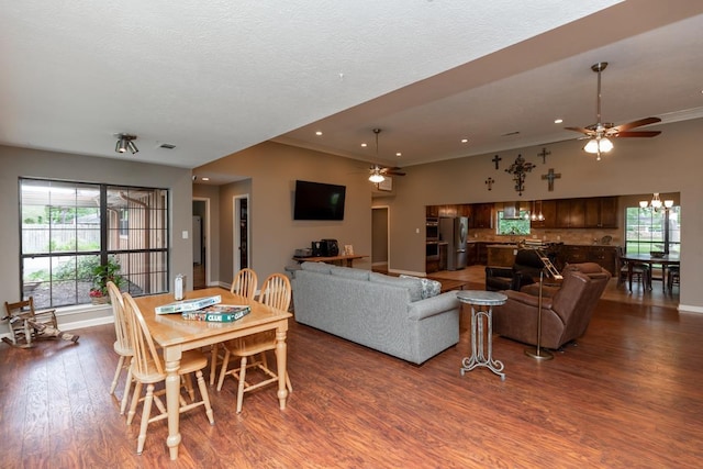 living room featuring baseboards, ceiling fan with notable chandelier, wood finished floors, and a wealth of natural light