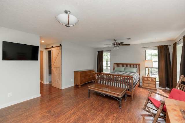bedroom with multiple windows, a barn door, and wood finished floors