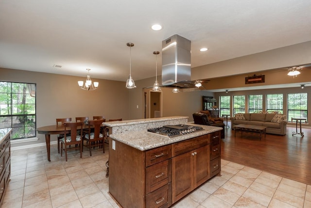 kitchen with island exhaust hood, plenty of natural light, ceiling fan with notable chandelier, and stainless steel gas stovetop