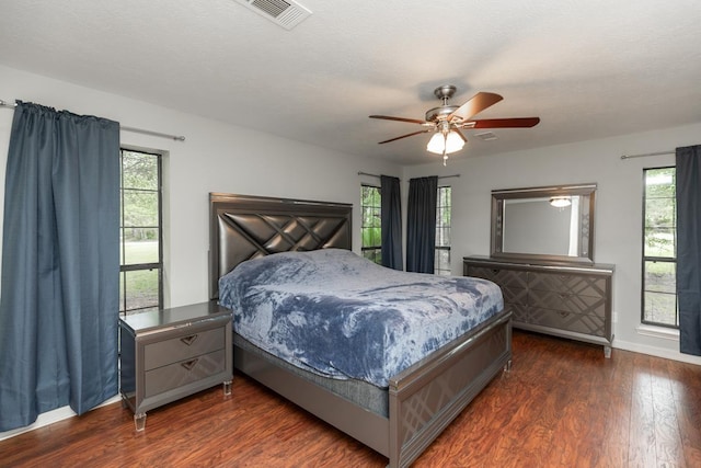 bedroom featuring baseboards, visible vents, dark wood-style floors, and multiple windows