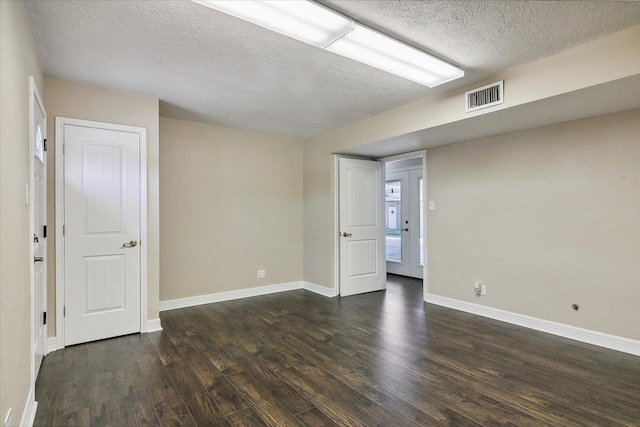 empty room with a textured ceiling and dark hardwood / wood-style flooring