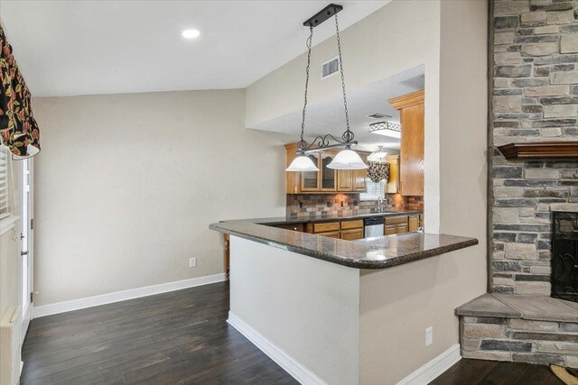 kitchen featuring dishwasher, backsplash, kitchen peninsula, dark stone countertops, and decorative light fixtures