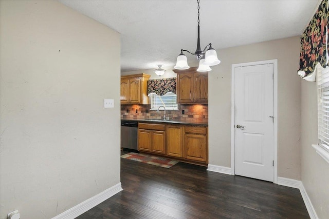 kitchen with tasteful backsplash, stainless steel dishwasher, sink, pendant lighting, and an inviting chandelier