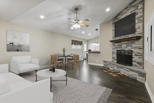 living room featuring ceiling fan, dark hardwood / wood-style flooring, lofted ceiling, and a fireplace