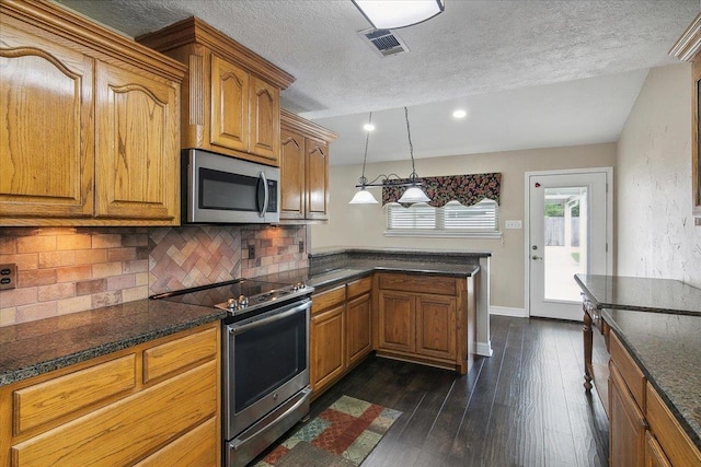 kitchen with dark wood-type flooring, stainless steel appliances, backsplash, decorative light fixtures, and a textured ceiling