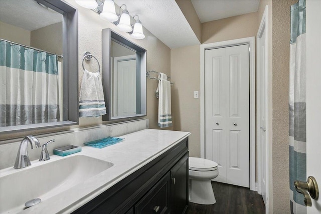 bathroom with wood-type flooring, vanity, a textured ceiling, and toilet