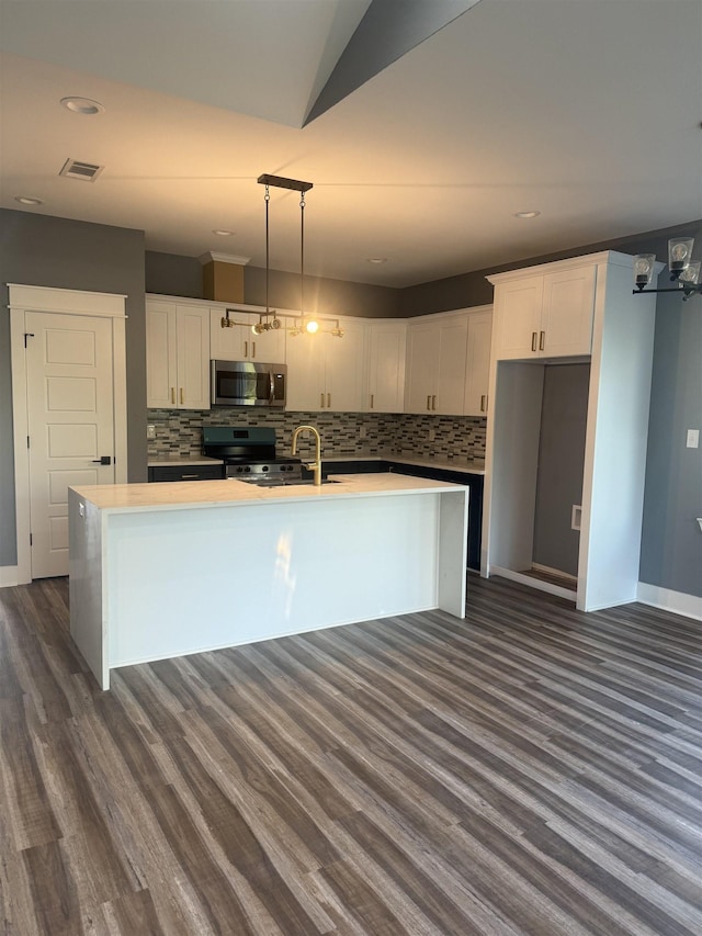 kitchen featuring white cabinets, appliances with stainless steel finishes, hanging light fixtures, and an island with sink