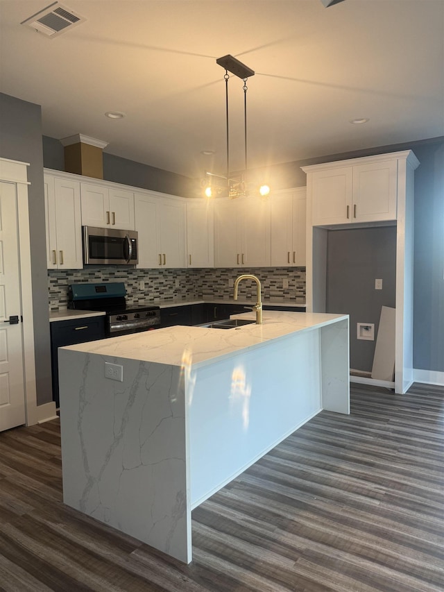 kitchen with pendant lighting, black range, a center island with sink, and white cabinetry