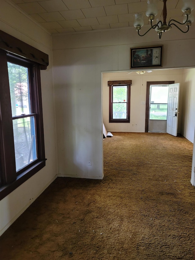 carpeted spare room with a notable chandelier