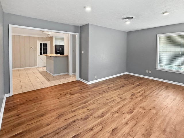 6215 Westgate Dr, Beaumont, TX 77706 - empty room with light wood-style flooring, baseboards, and a textured ceiling