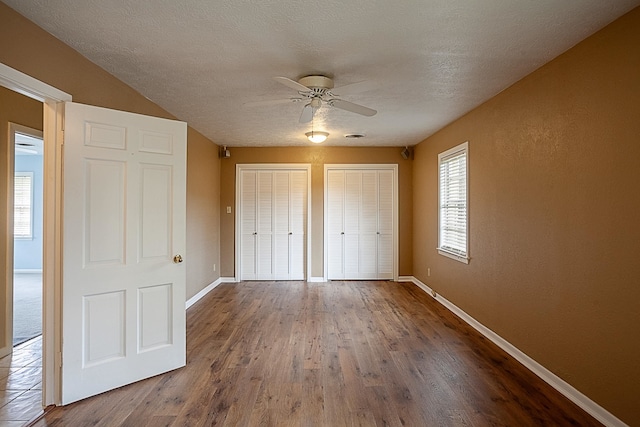 6215 Westgate Dr, Beaumont, TX 77706 - unfurnished bedroom with two closets, baseboards, wood finished floors, a ceiling fan, and a textured ceiling