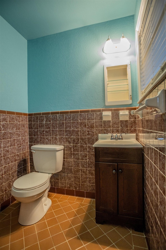 bathroom with tile patterned flooring, vanity, toilet, and tile walls