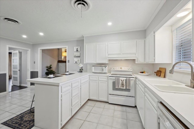 kitchen featuring white appliances, a sink, a peninsula, white cabinetry, and light countertops