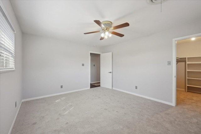 unfurnished bedroom with a spacious closet, carpet floors, a closet, baseboards, and ceiling fan