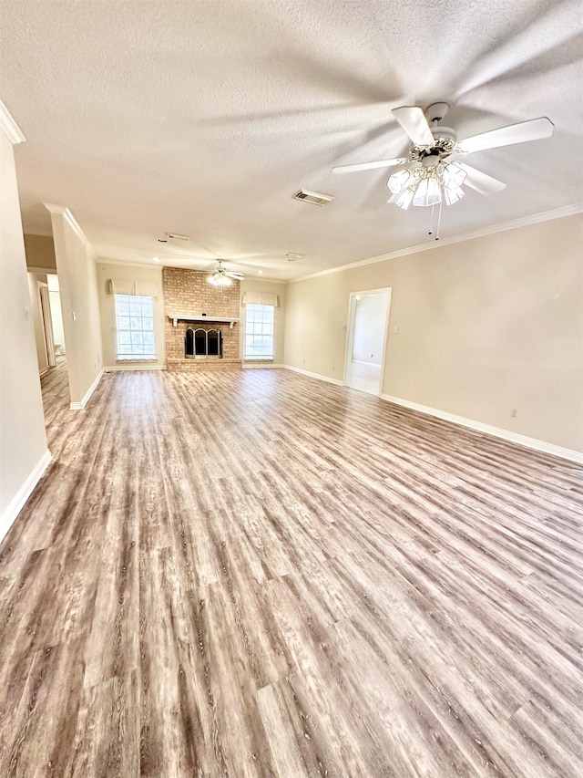 unfurnished living room featuring a wealth of natural light, crown molding, ceiling fan, and a textured ceiling