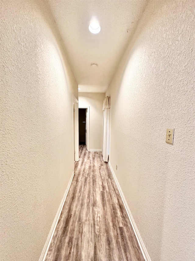 corridor with a textured ceiling and hardwood / wood-style flooring