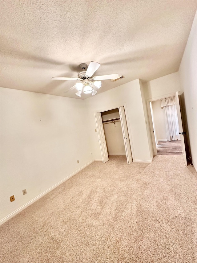 unfurnished bedroom featuring ceiling fan, light carpet, and a textured ceiling