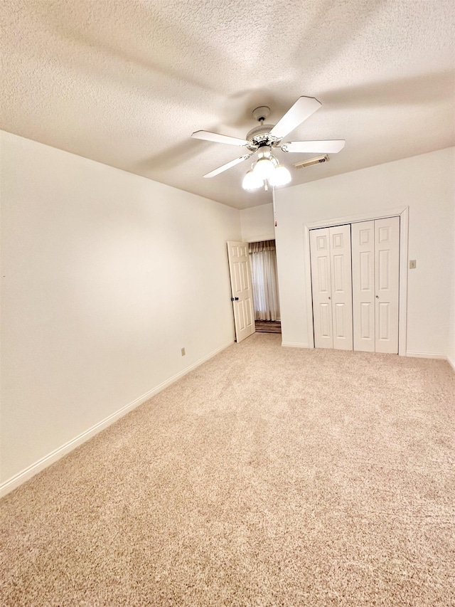 unfurnished bedroom with carpet, a textured ceiling, a closet, and ceiling fan