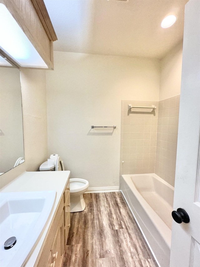 full bathroom with vanity, toilet, wood-type flooring, and tiled shower / bath