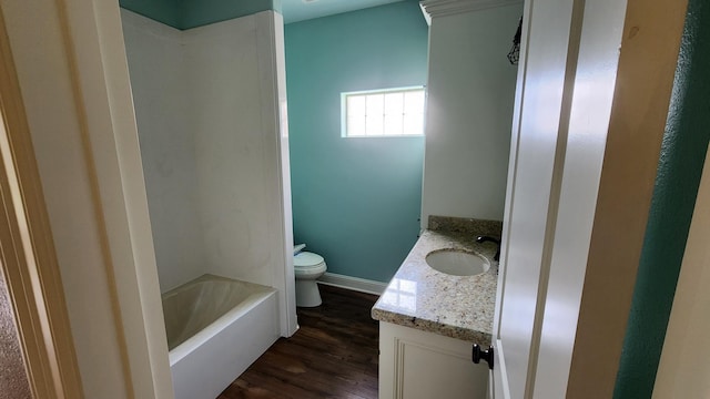 full bath with wood finished floors, toilet, vanity, a bathing tub, and baseboards