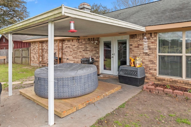 view of patio / terrace with french doors, a hot tub, and fence