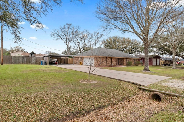 view of yard with a garage, driveway, and fence