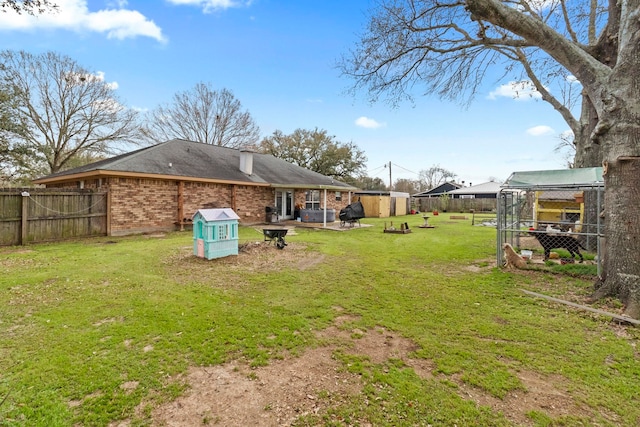 view of yard with an outbuilding, a fenced backyard, an outdoor fire pit, and exterior structure