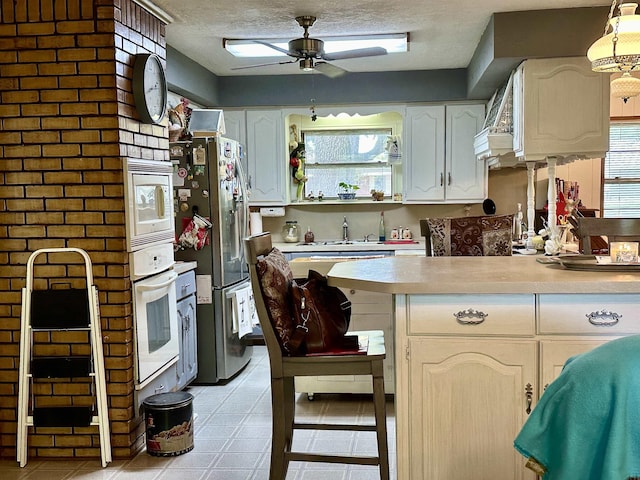 kitchen with ceiling fan, sink, white cabinetry, a textured ceiling, and white appliances