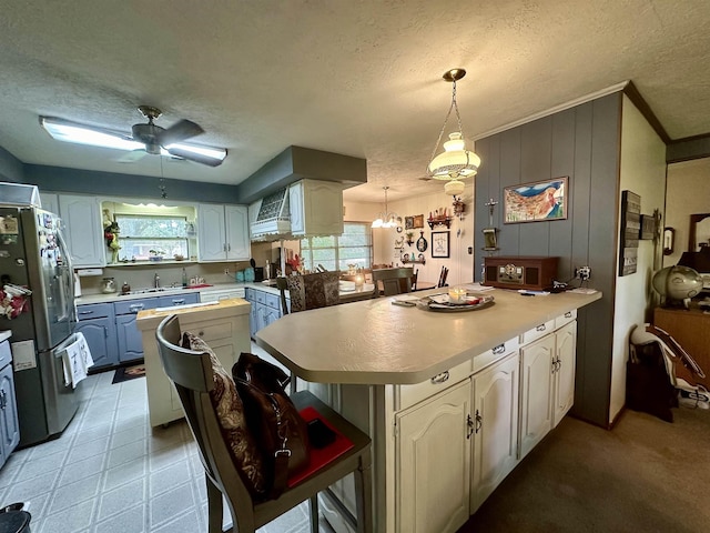 kitchen with a kitchen breakfast bar, stainless steel refrigerator, pendant lighting, and a textured ceiling