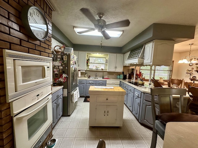 kitchen featuring stainless steel refrigerator, built in microwave, white oven, butcher block countertops, and black electric stovetop