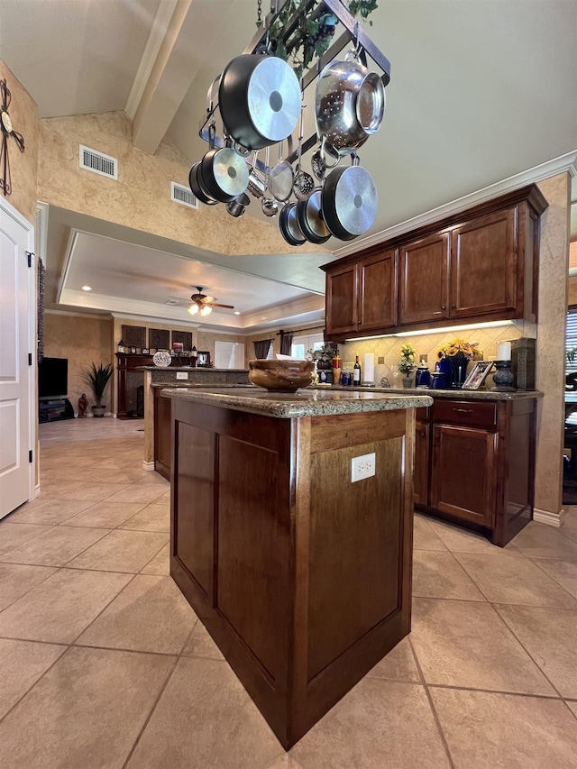 5770 Scenic Dr, Beaumont, TX 77713 - kitchen with a kitchen island, dark brown cabinetry, decorative backsplash, a ceiling fan, and a tray ceiling
