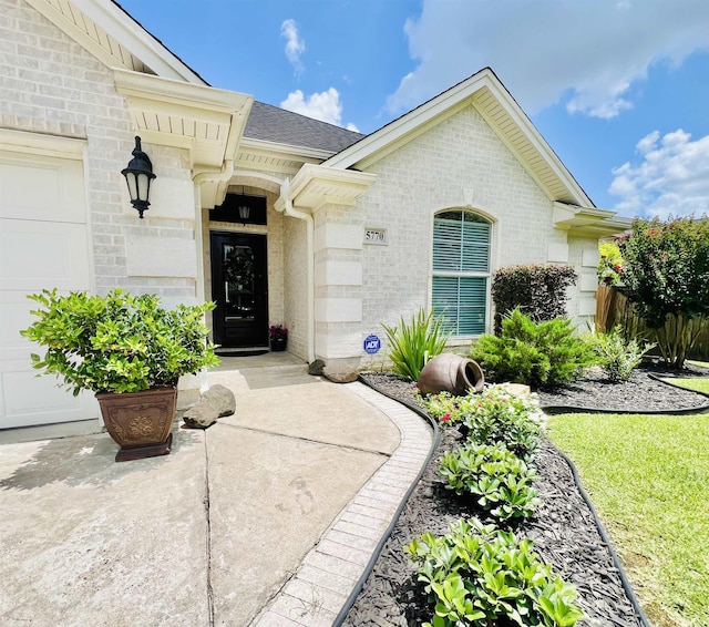 5770 Scenic Dr, Beaumont, TX 77713 - view of exterior entry with brick siding, a garage, and roof with shingles