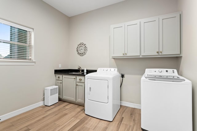 laundry area with washer and dryer, cabinets, sink, and light hardwood / wood-style flooring